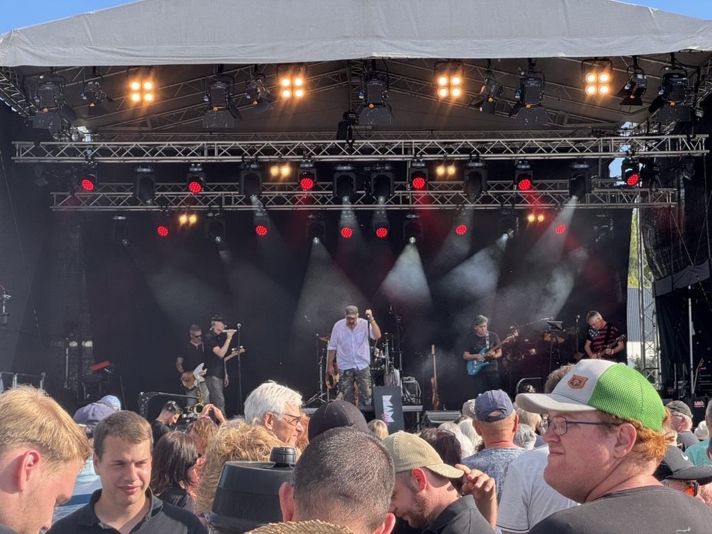 Band auf einer Open-Air-Bühne mit Lichtshow vor Publikum