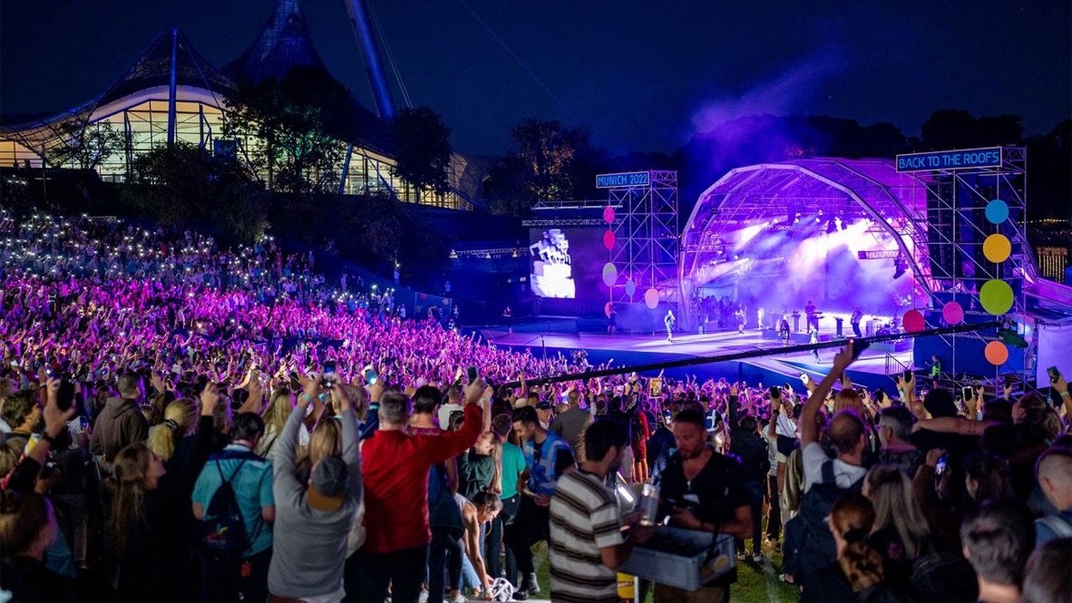 Konzert bei Nacht vor der Bühne „Back to the Roofs“ im Münchner Olympiapark mit jubelndem Publikum