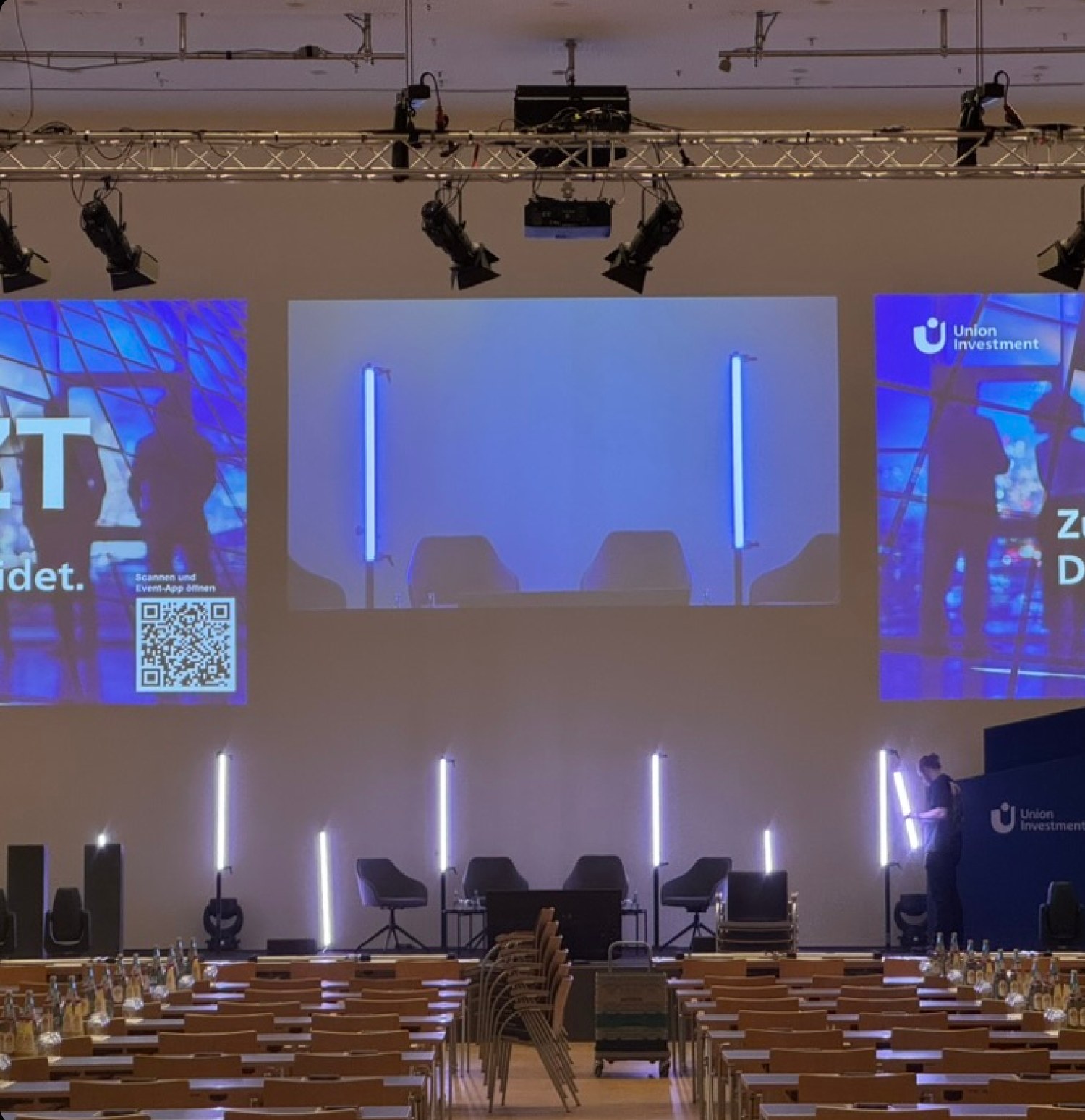 Vorbereitete Konferenzbühne mit Leinwänden, Lichttechnik und Stuhlreihen