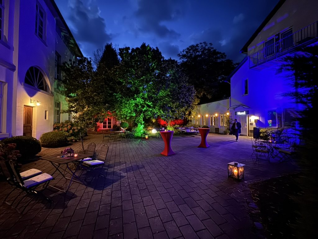 Abendlich beleuchteter Hotel-Innenhof mit Stehtischen